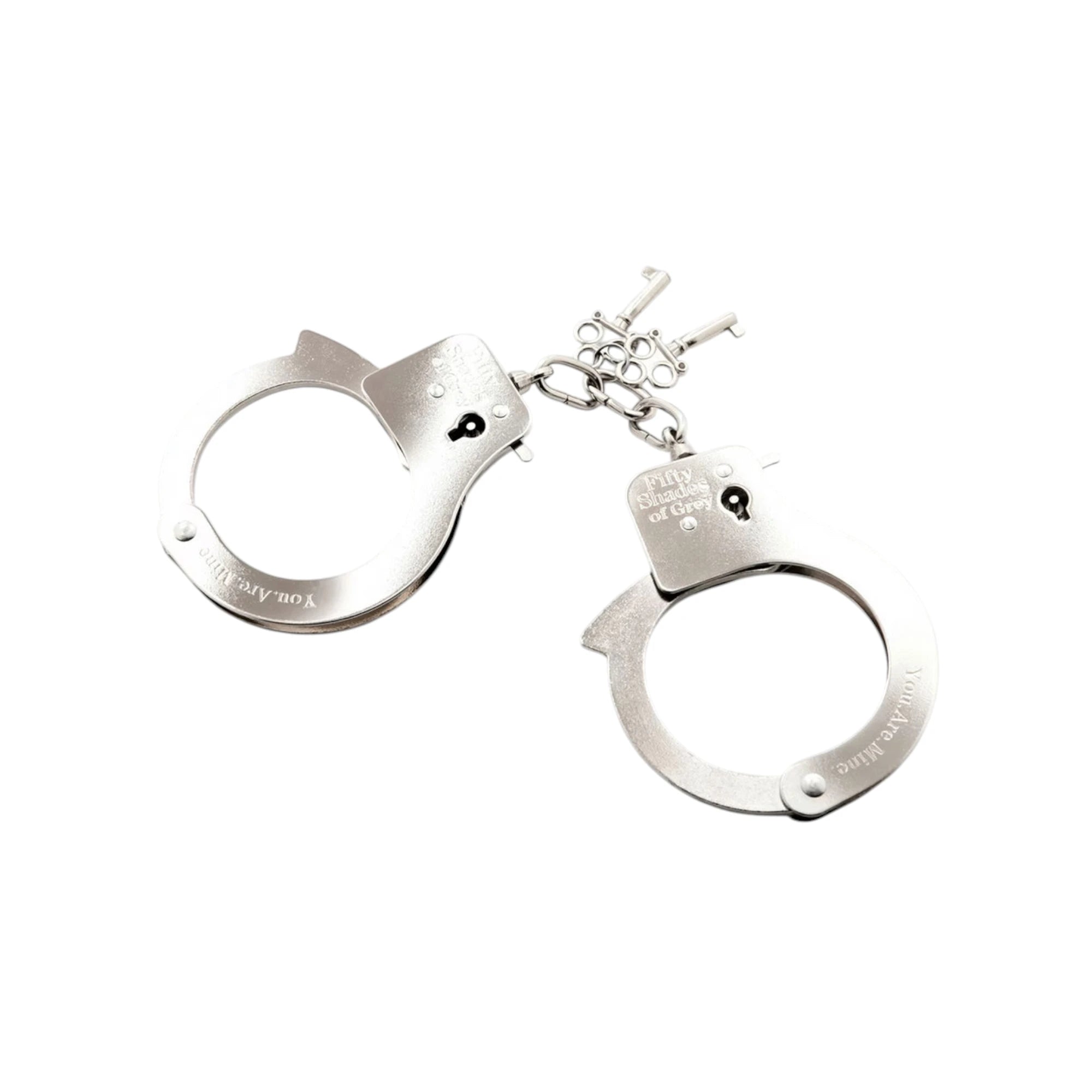 Fifty Shades of Grey You. Are. Mine. metal handcuffs shown as connected pair displaying polished silver metal cuffs with 'You.Are.Mine' and 'Fifty Shades of Grey' branding, metal chain connector, and two silver keys against white background