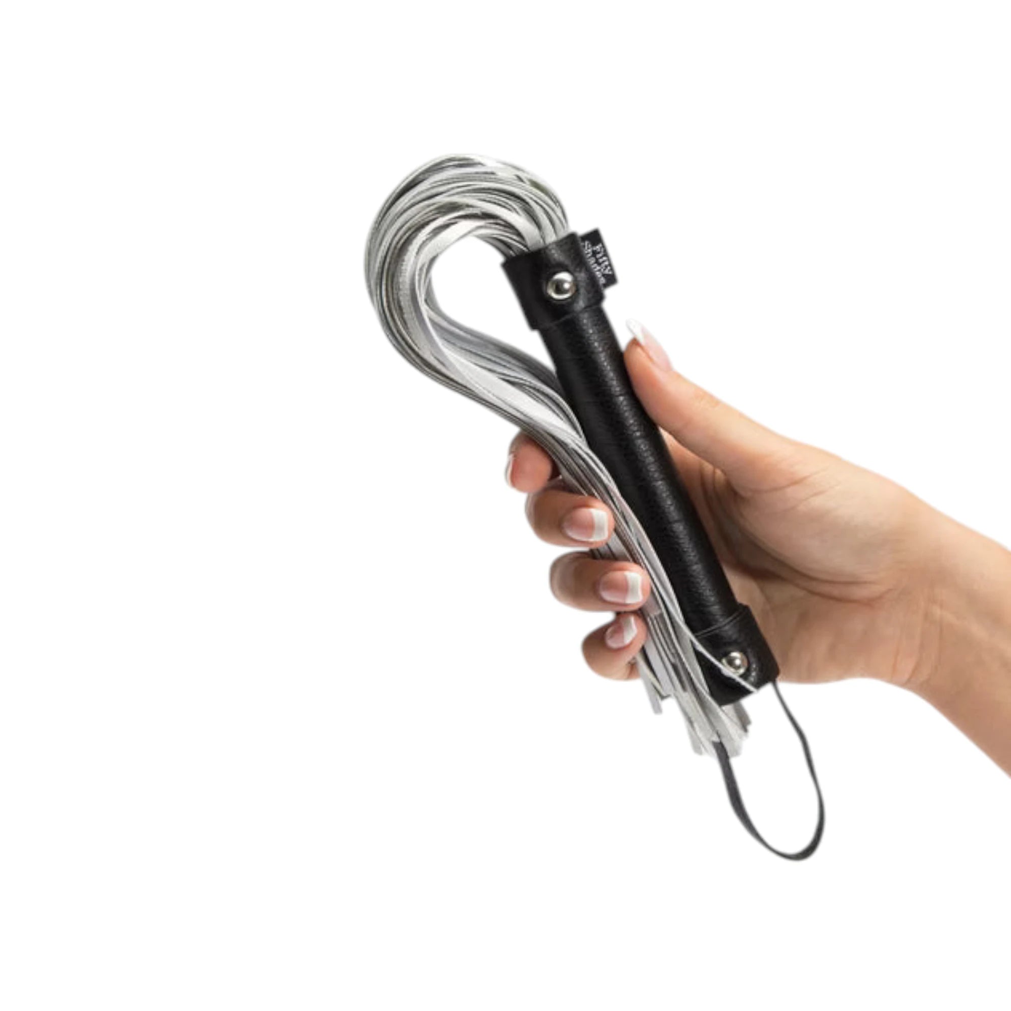 Fifty Shades of Grey Please, Sir black flogger held in hand displaying black textured handle with metal rivets, multiple white and grey leather strands gathered at top, wrist loop, and compact handheld size against white background