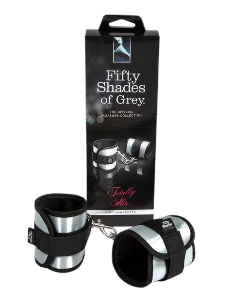 Fifty Shades of Grey Totally His soft handcuffs packaging box in dark grey with handle displaying 'Fifty Shades of Grey The Official Pleasure Collection' branding, product images of connected handcuffs, 'Totally His' text in purple, and 'Soft Handcuffs' label against white background