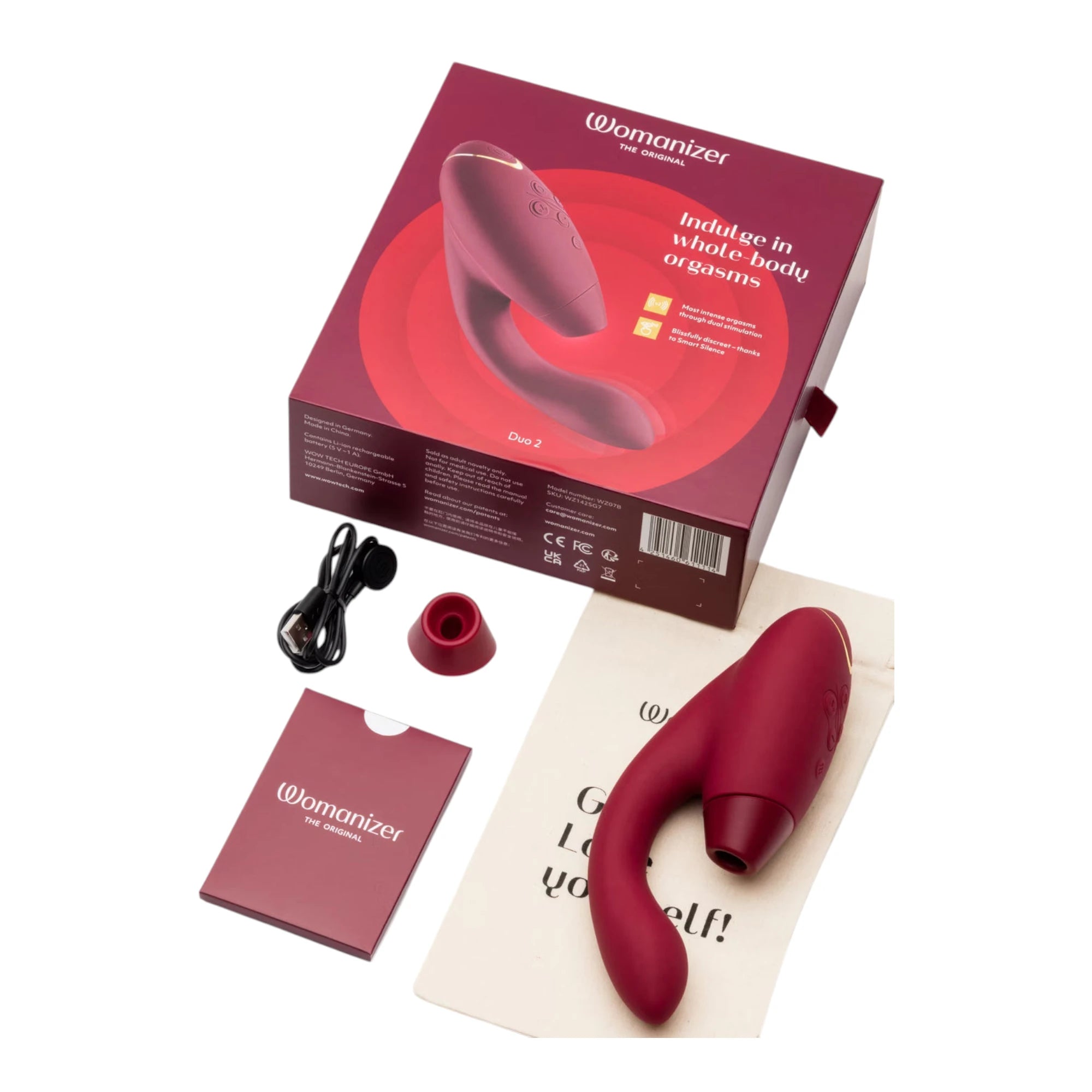 Womanizer Duo 2 burgundy dual stimulator unboxed showing product, charging cable, storage pouch, and instruction booklet against white background