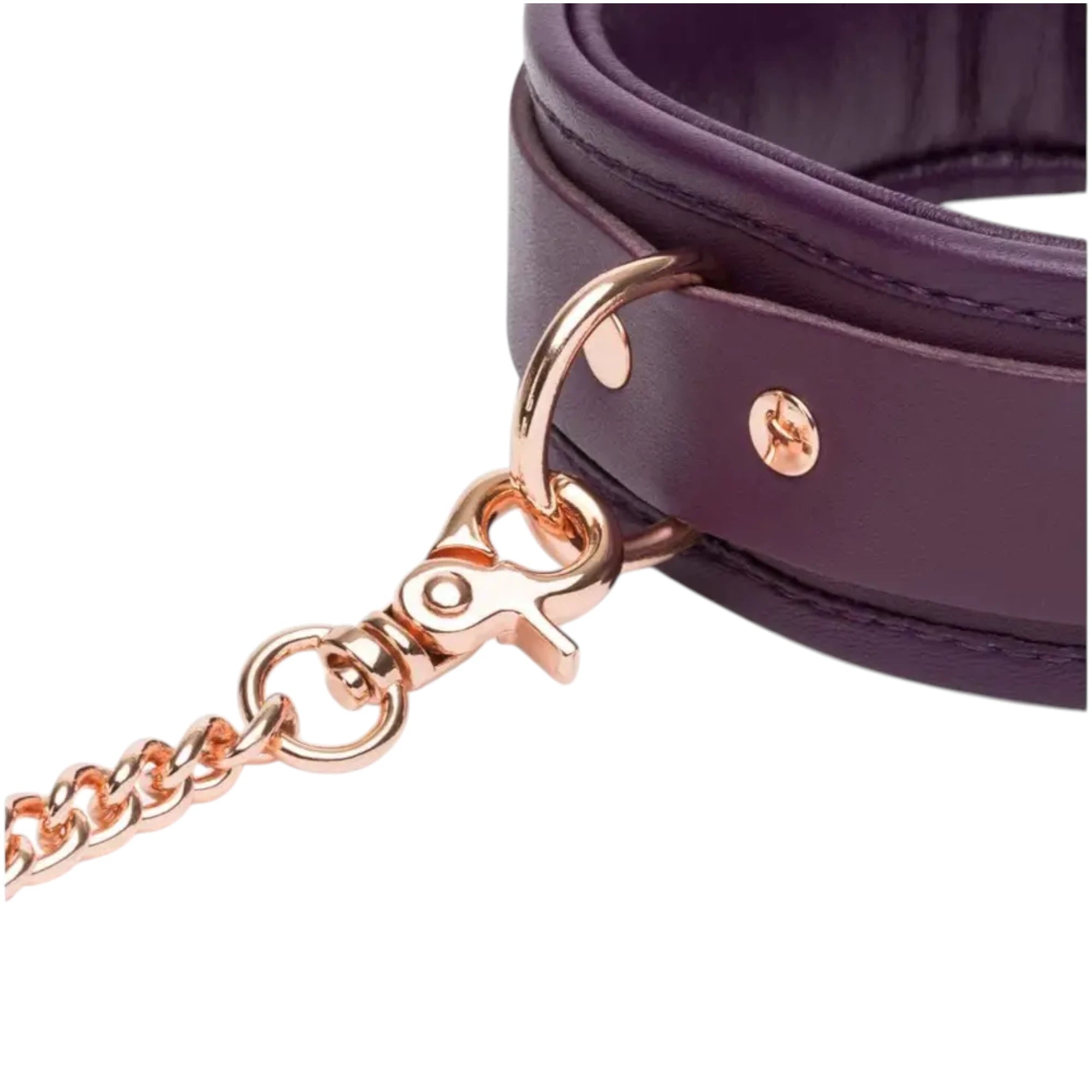  Close-up of the Fifty Shades Freed Cherished Collection leather collar hardware, showing the purple padded collar with rose-gold rivets, D-ring attachment and the rose-gold chain lead clip connected against a white background.