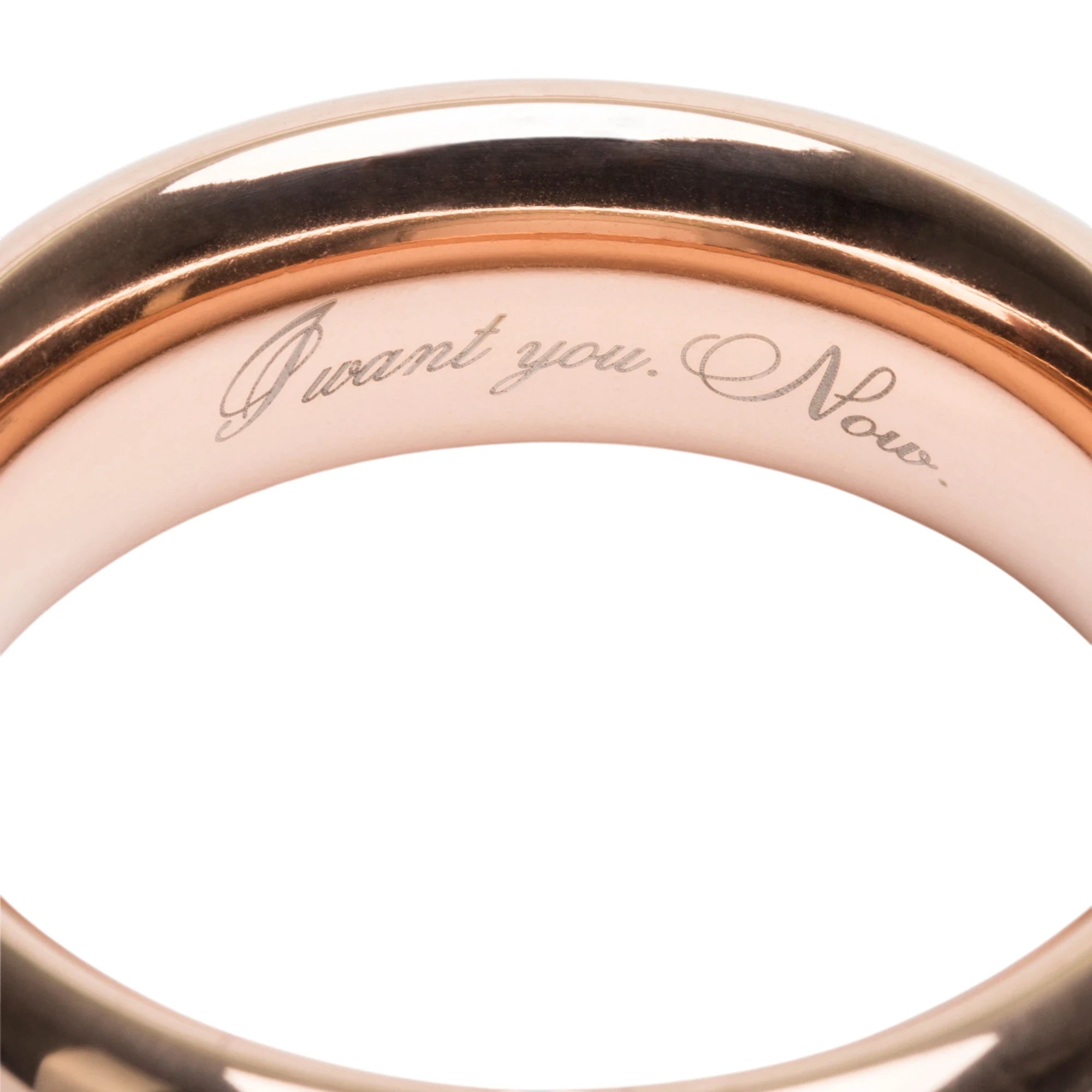 Close-up of the Fifty Shades Freed “I Want You Now” steel love ring engraving, showing the “I want you. Now.” text etched on the inside of the rose-gold band against a white background