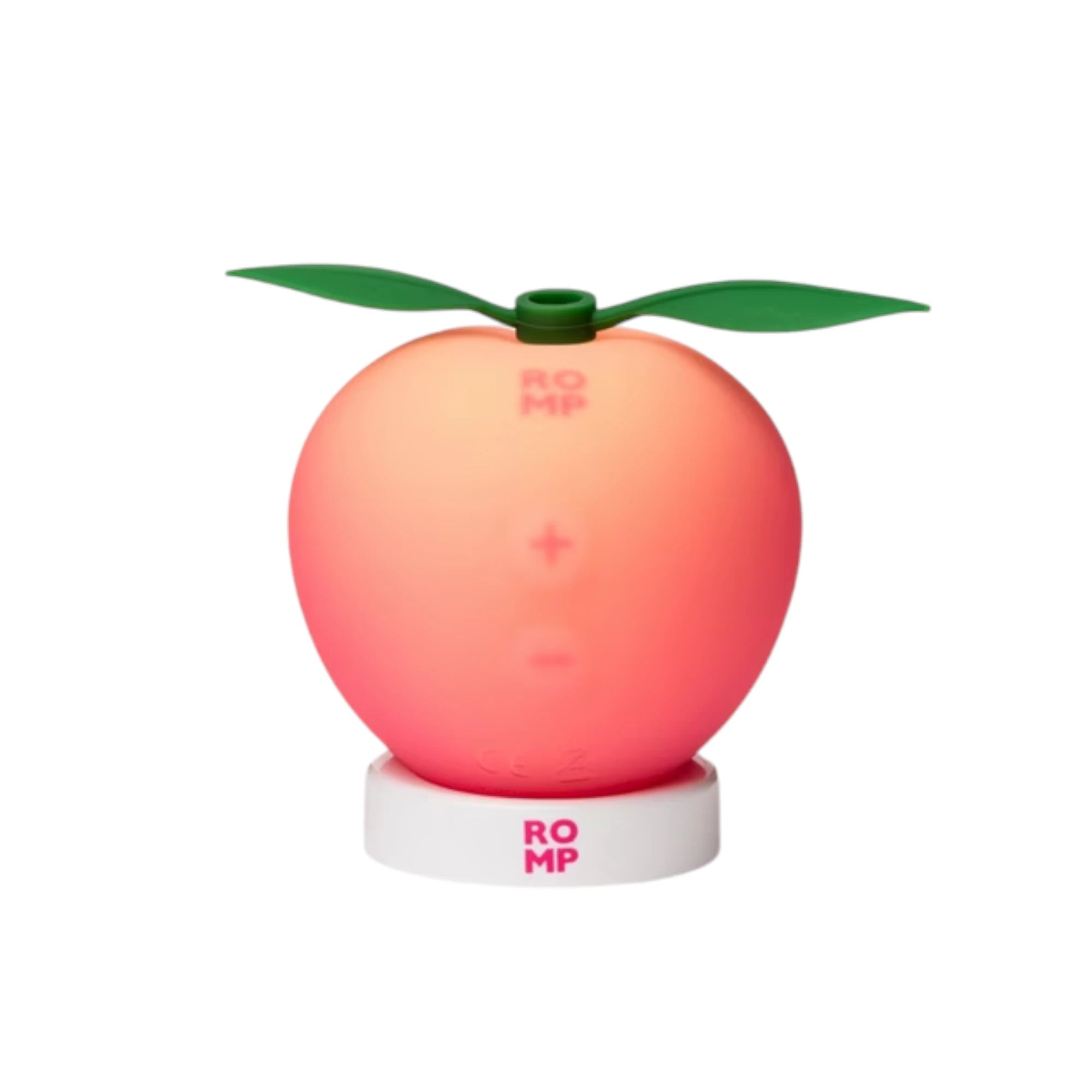 The ROMP Pink Peach rechargeable clitoral stimulator in peach-shaped pink silicone with two green leaf details on top and a white charging stand with ROMP branding, shown on a plain white background