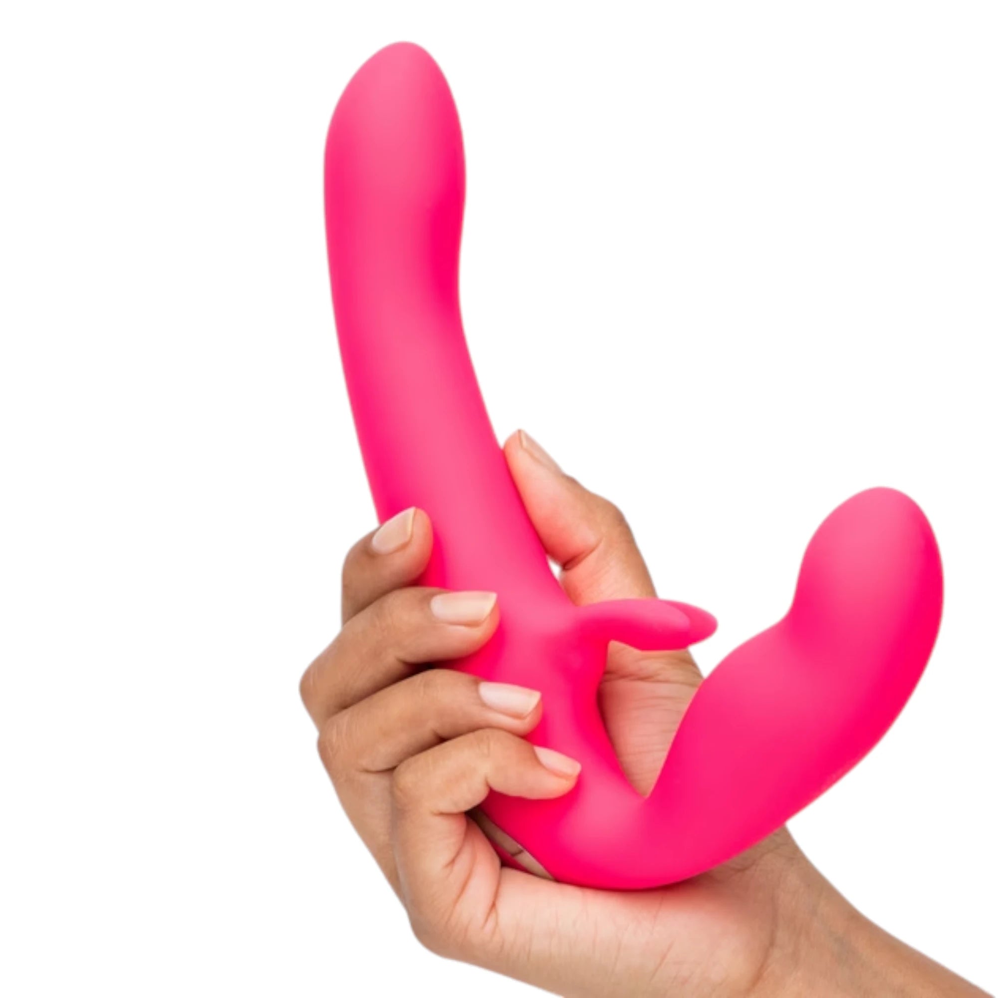 Happy Rabbit vibrating strapless strap-on in hot pink held in hand displaying curved dual-ended design, external rabbit ear stimulator, and smooth silicone finish against white background