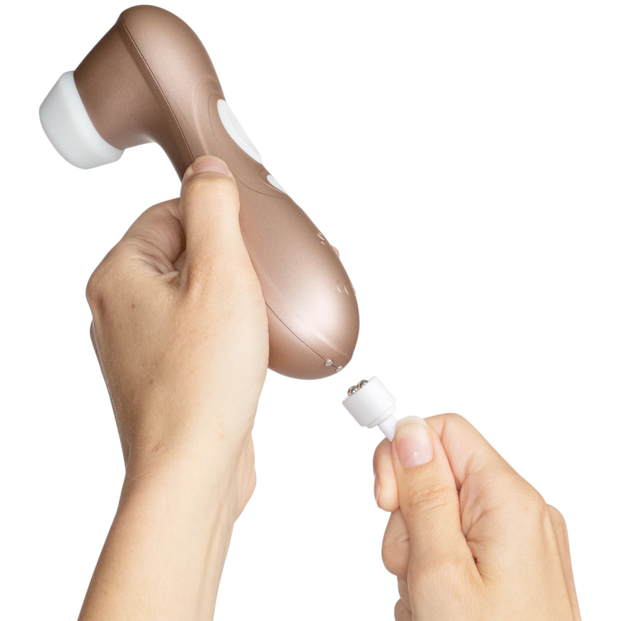 The Satisfyer Pro 2 Generation 2 clitoral stimulator in rose gold with a curved handle and a white silicone suction head, shown held in hands with a white magnetic charging cable positioned near the charging contacts, against a plain white background
