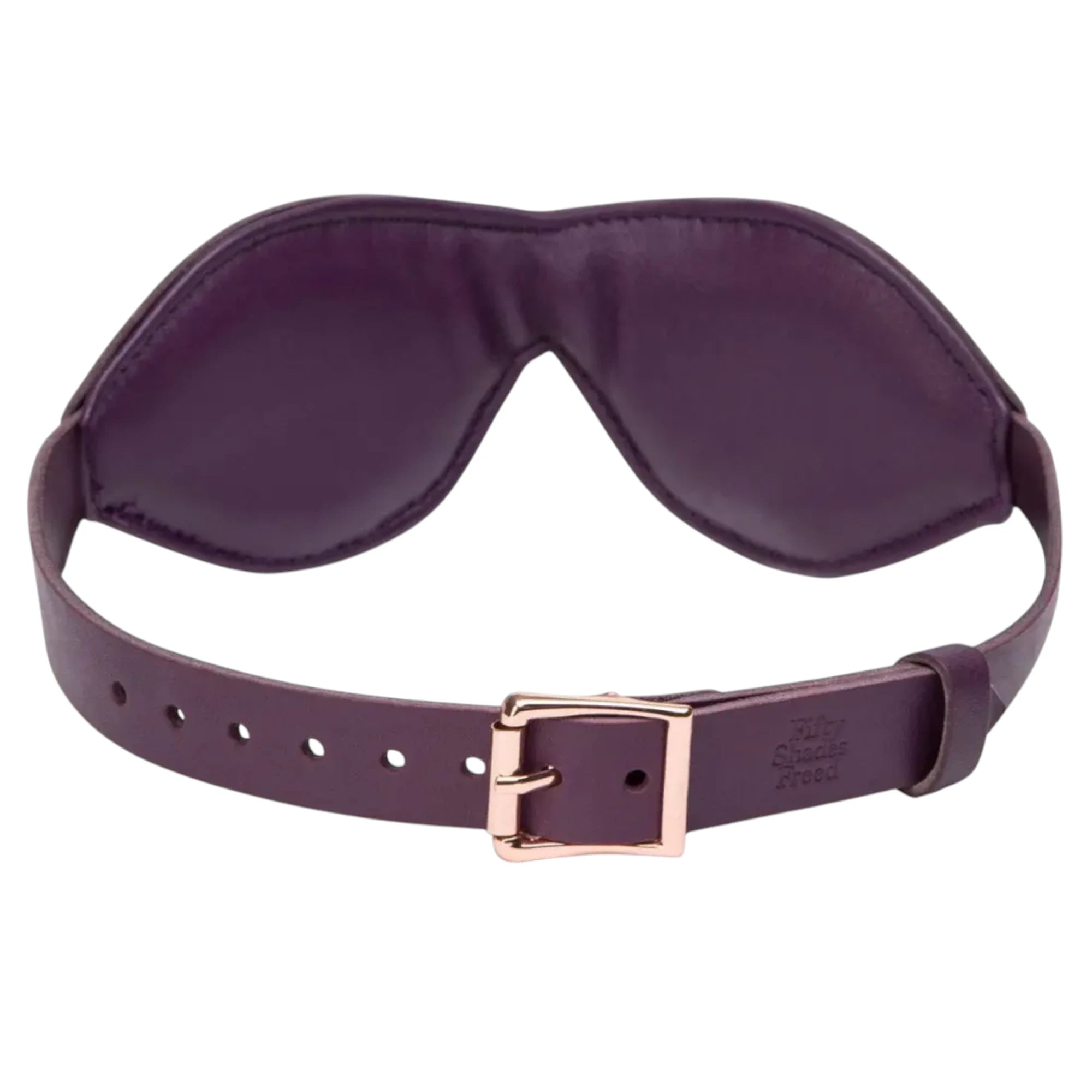 Angled view of the Fifty Shades Freed Cherished Collection purple leather blindfold, showing the padded stitched eye cover and the adjustable strap with rose-gold buckle hardware against a white background