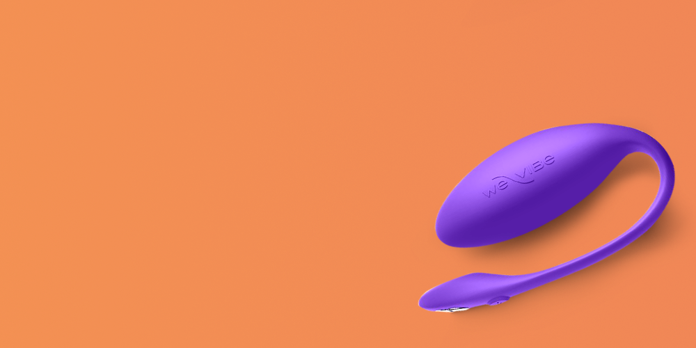 We-Vibe couples vibrator in vibrant purple silicone with a curved, ergonomic design featuring a rounded bulb for internal stimulation and an external arm for clitoral contact, with embossed branding visible on the surface, positioned on the right side of a warm peachy-orange background with large empty space on the left