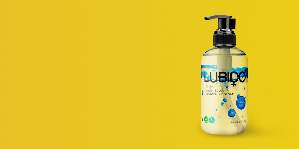 Lubido Original water-based intimate lubricant in a clear cylindrical bottle with a black pump dispenser, featuring a white label with blue water droplet graphics and text reading 'LUBIDO Original Water Based Intimate Lubricant' with ingredient icons and 250ml volume marking, positioned on the right side of a bright golden-yellow background with large empty space on the left.