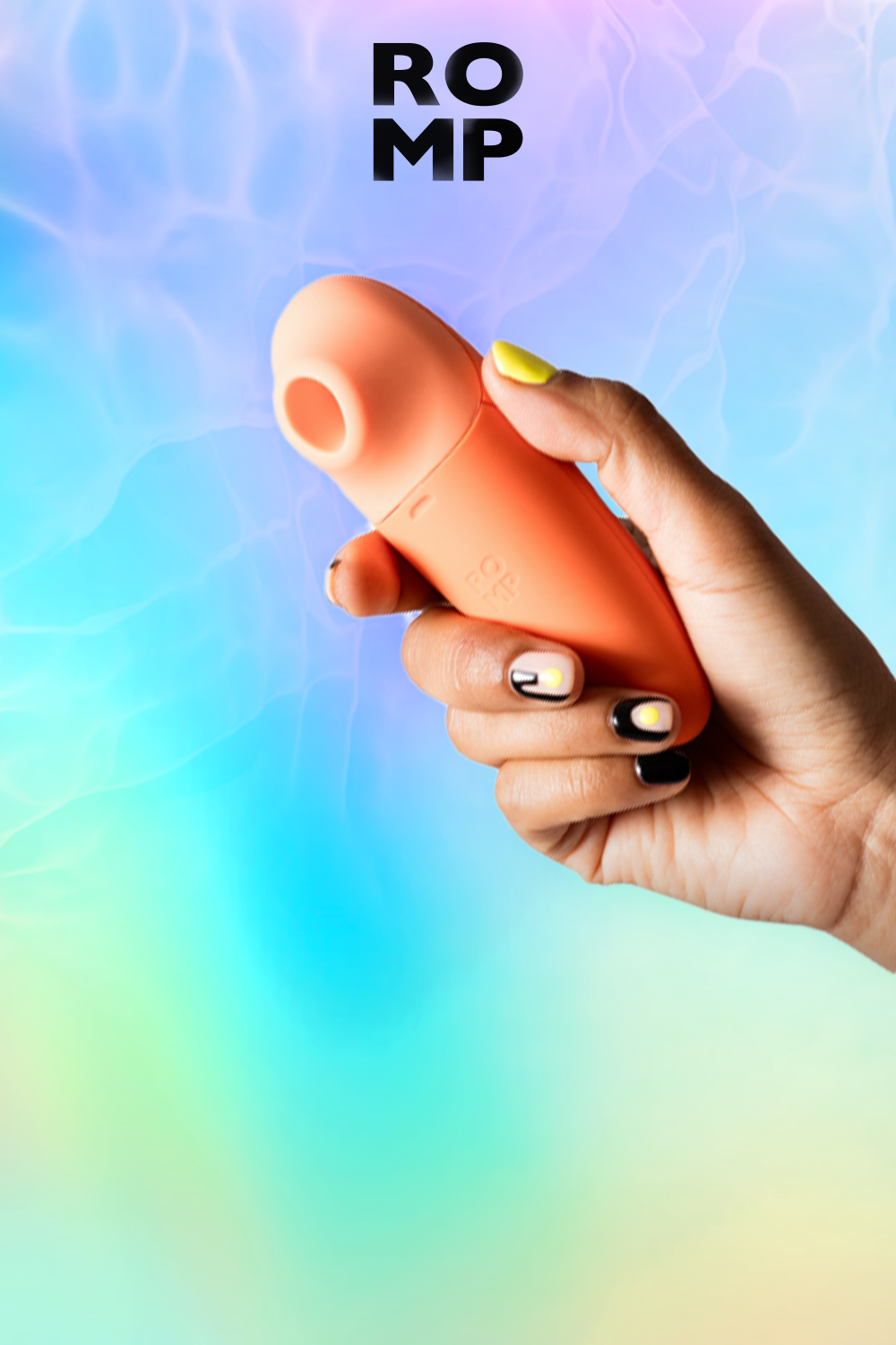 Hand holding a terracotta-orange clitoral suction toy with a rounded, bulbous head and textured ridged body against a soft gradient background transitioning from blue at the top through pink and purple to pale yellow-green at the bottom; the person's hand has black and white geometric nail art with a yellow-painted nail visible at the top; bold black sans-serif text reading 'ROMP' is positioned in the upper center of the image
